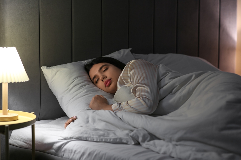 Beautiful young woman sleeping in bedroom at night
