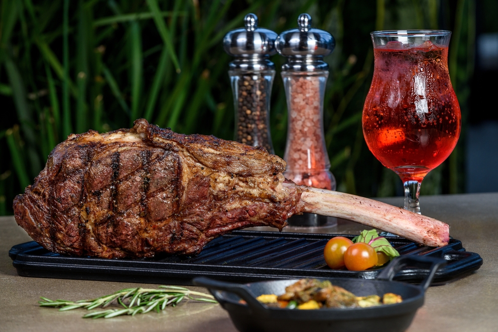 Tomahawk steak on cast iron grill, served with creamy mashed potatoes, rosé wine and seasoned with salt and pepper. Perfect blend of flavors and gourmet presentation for a unique culinary experience