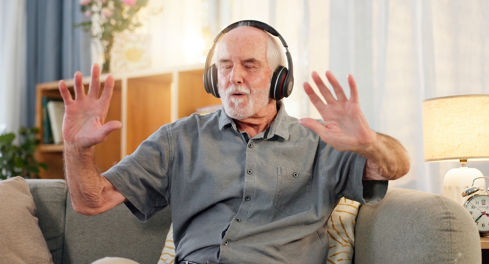 Old man, headphones and dancing in home, music and having fun in retirement or streaming sound. Elderly male person, playlist and living room hip hop for audio therapy, freedom and listening on sofa