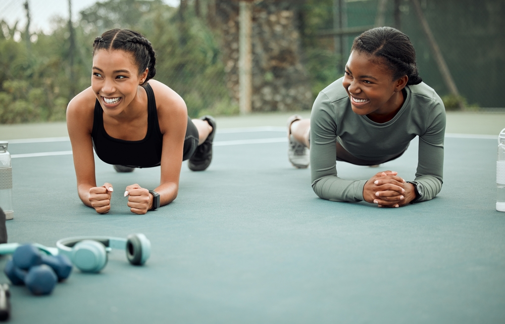 Outdoor, fitness and women with plank for morning exercise, balance or core workout routine. Court, athlete and friends with smile for endurance challenge, physical activity or muscle gain in Atlanta