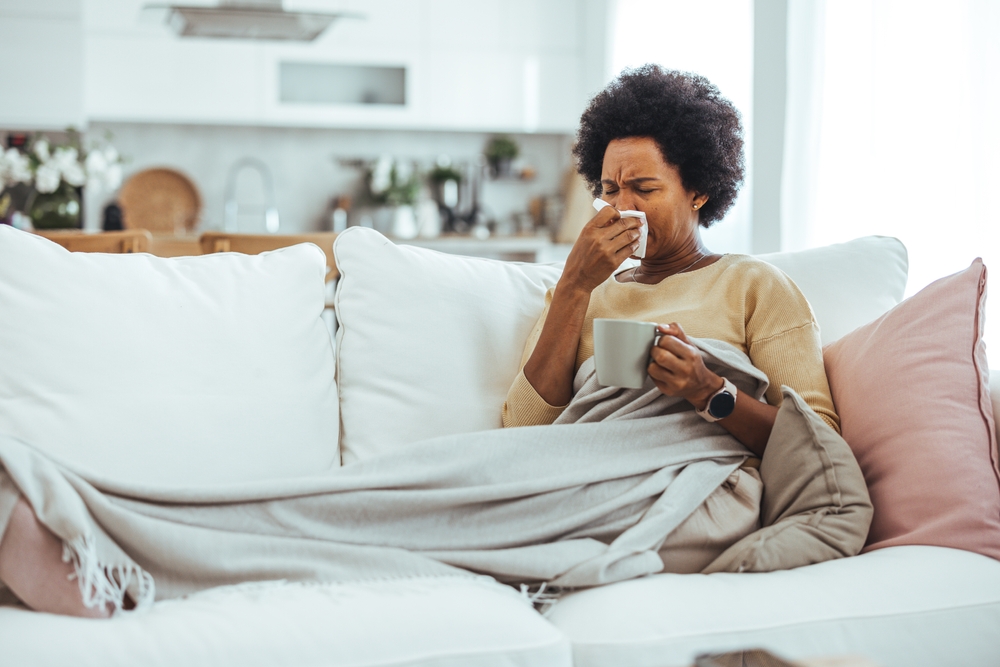 Woman with flu in bed, she use home medicine to handle sickness. Ill Woman Caught Cold, Feeling Sick And Sneezing In Paper Wipe. Closeup Of Beautiful Unhealthy Girl Covered In Blanket Wiping Nose.
