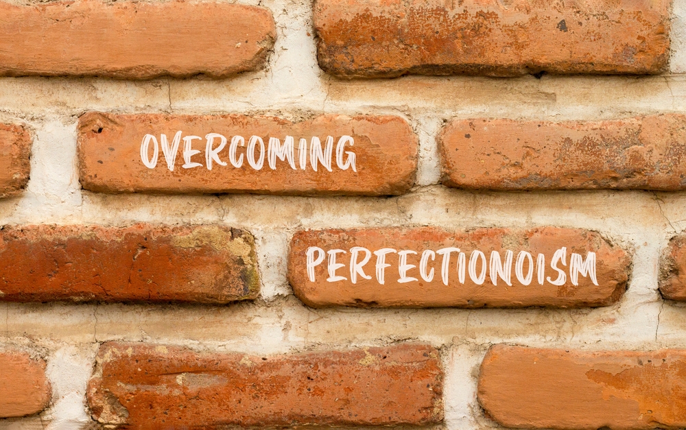 Overcoming perfectionism symbol. Concept words Overcoming perfectionism on beautiful brick wall. Beautiful red brown brick wall background. Business Overcoming perfectionism concept. Copy space.