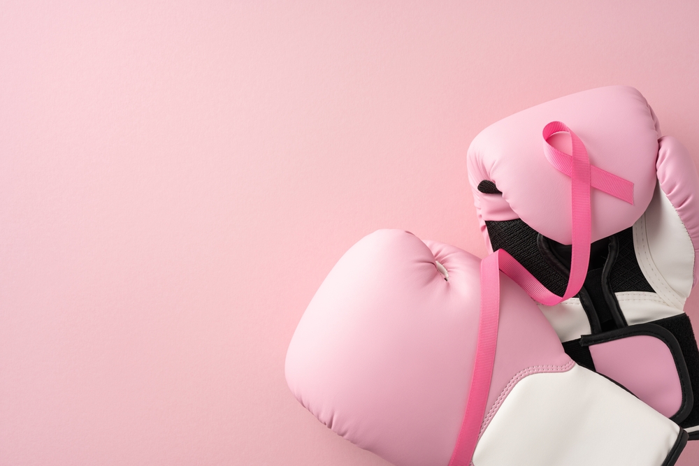 Pink boxing gloves with a pink ribbon highlight breast cancer awareness and strength against cancer
