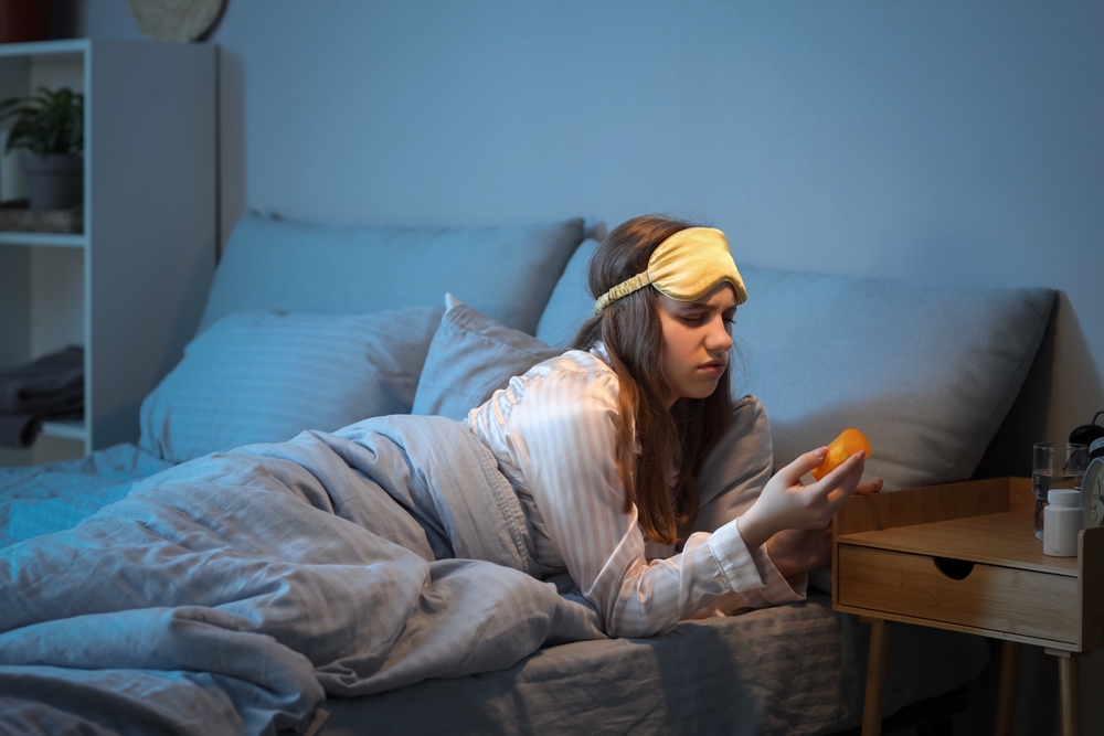 Young woman taking sleeping pills in bed at night
