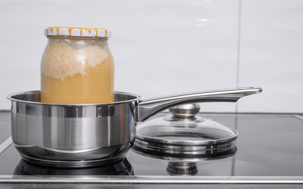 Decrystallization of bee honey, a jar of honey is standing in a pot