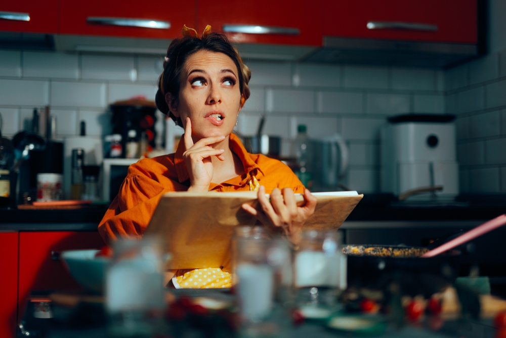 Housewife Holding a Cookbook Thinking What to Make for Dinner. Undecided woman making plans for dinner and lunch