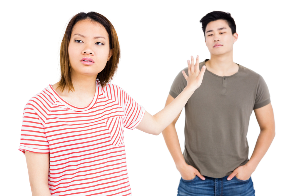 Young couple ignoring each other on white background
