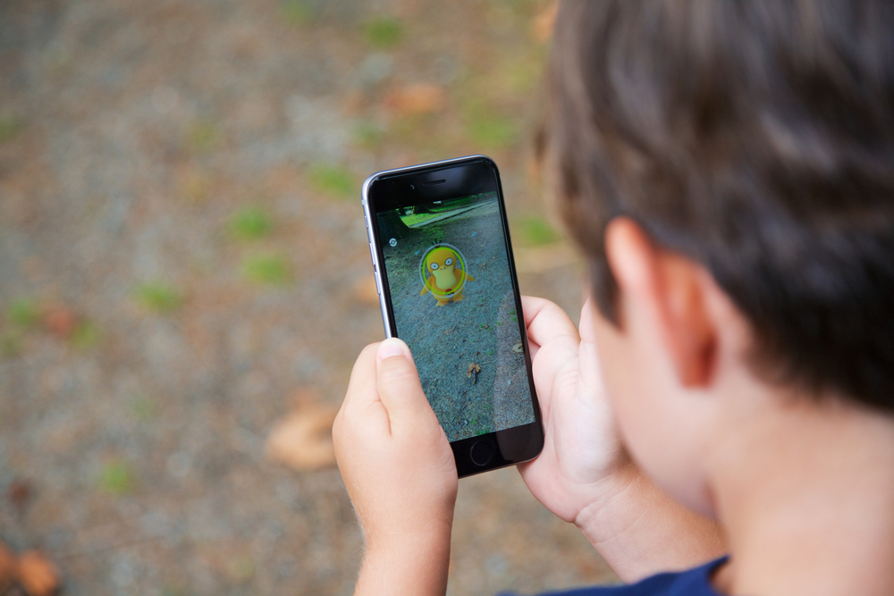 VANCOUVER, CANADA - JULY 22, 2016: A young boy outside playing Pokemon Go on a smart phone.
