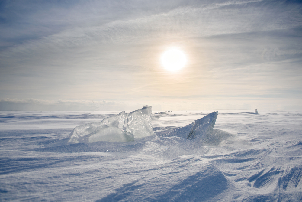 Boundless icy landscape during a snowstorm at sunset in winter.
