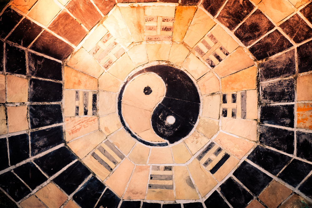 yin yang symbol on tiled wall with sunlight
