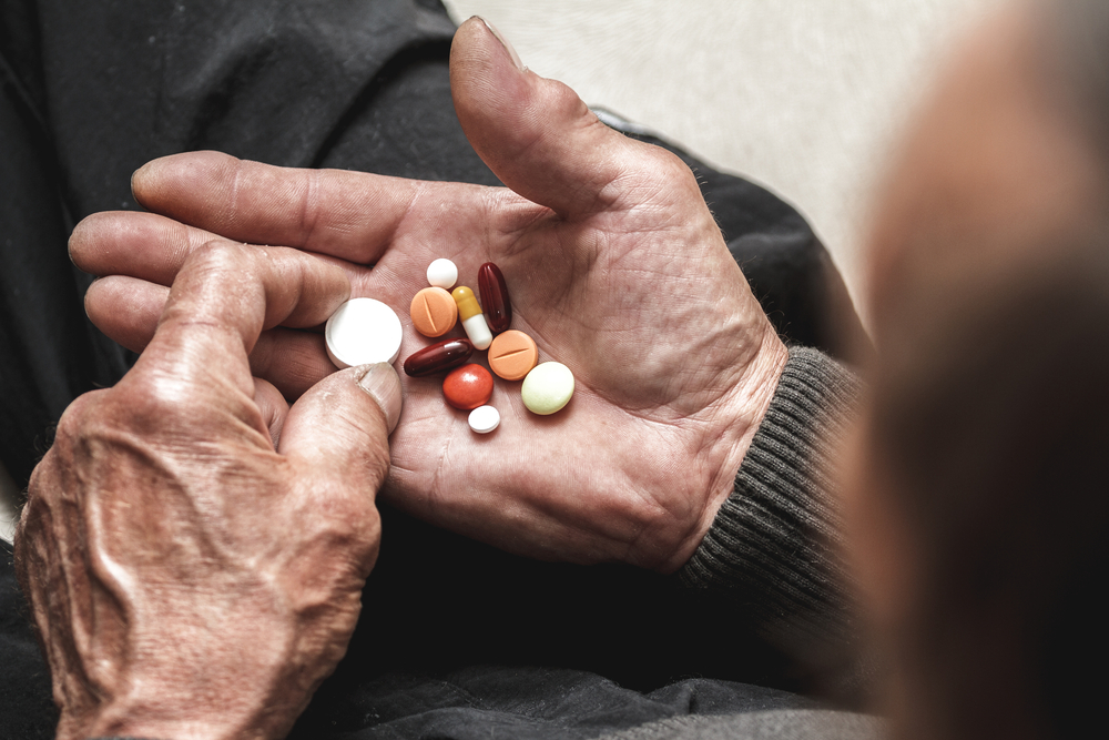 Many multi-colored pills in a Senior's hands. Painful old age. Caring for the health of the elderly
