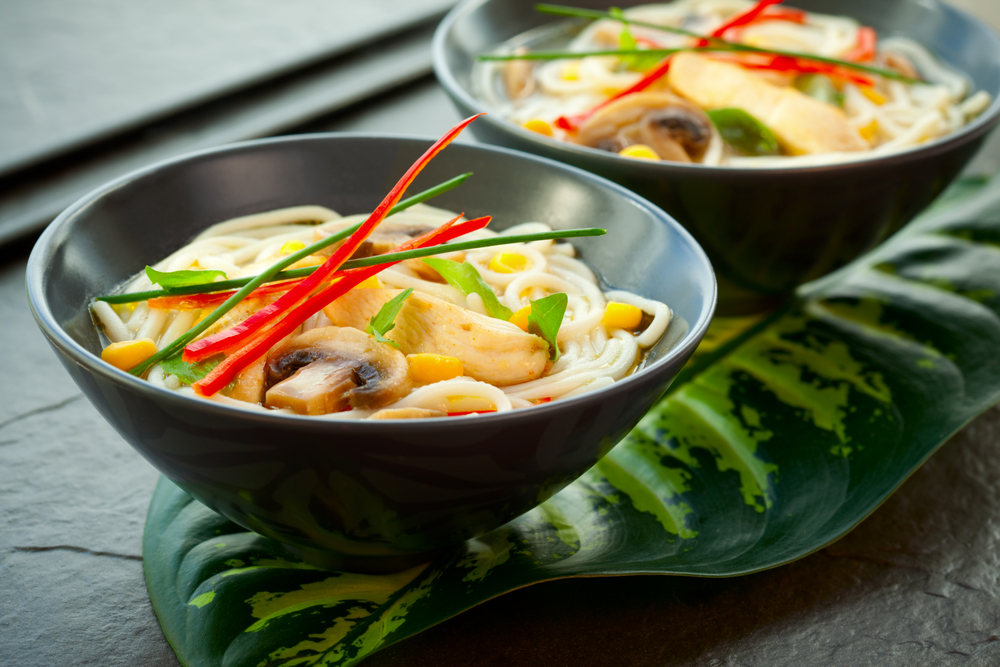 Bowls of Asian noodle soup with chicken,mushrooms, sweetcorn and chili