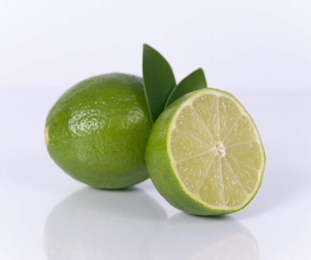 A lime and half a lime with leaves. White background.