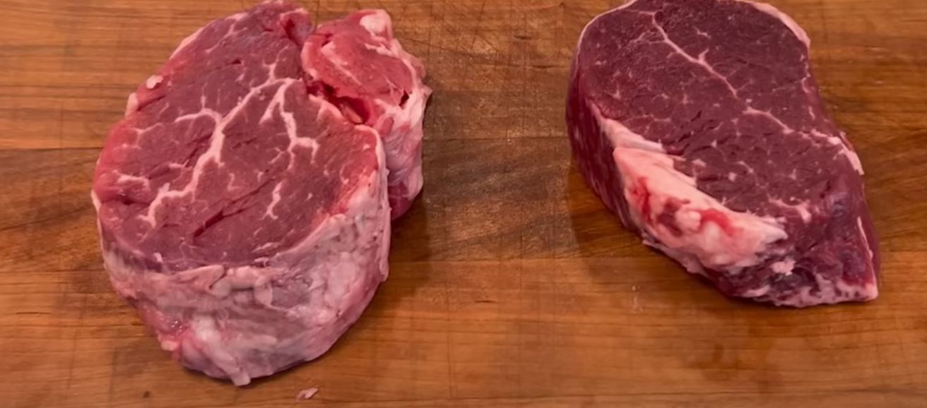 Two steaks on a wood block.