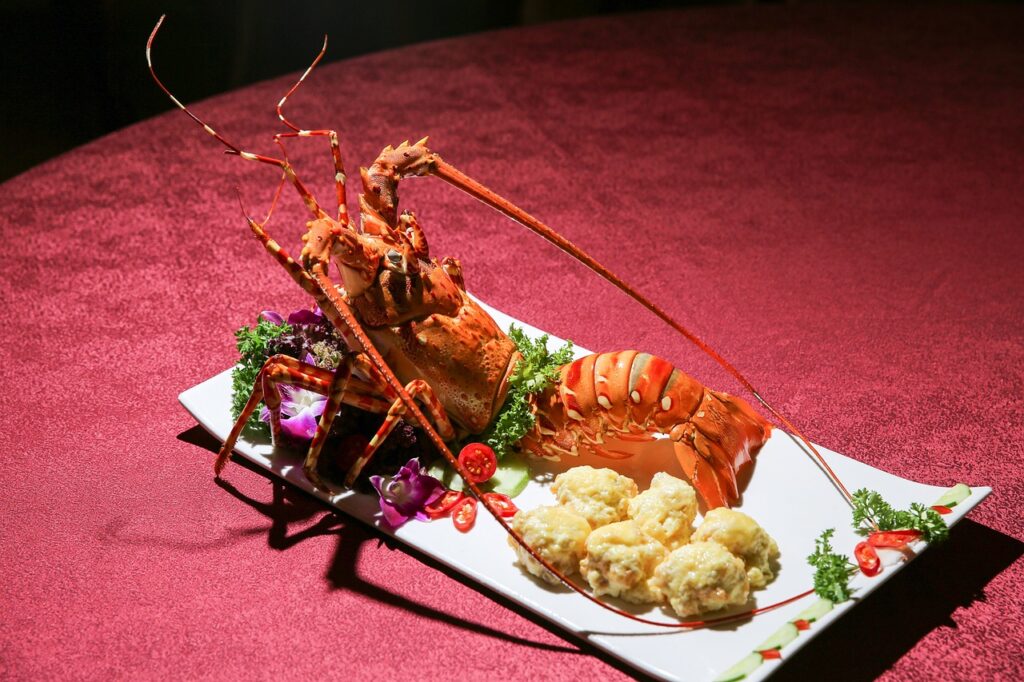 A lobster dish served with garnishes. Red table cloth in the background.
