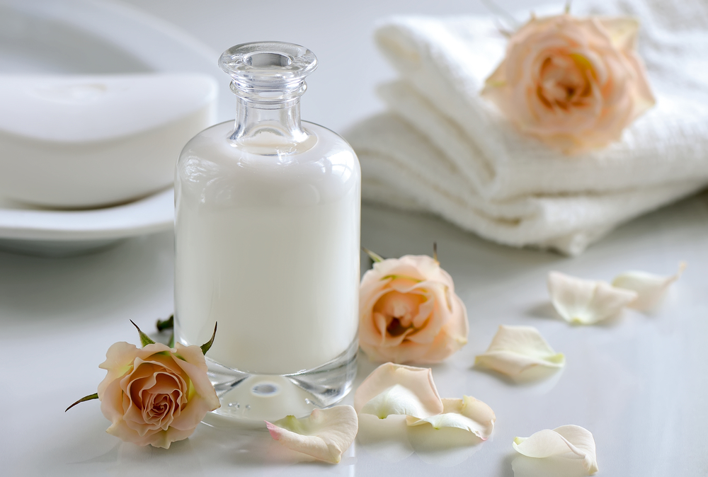 Body or face natural care lotion or bath milk decorated with rose flowers and petals
