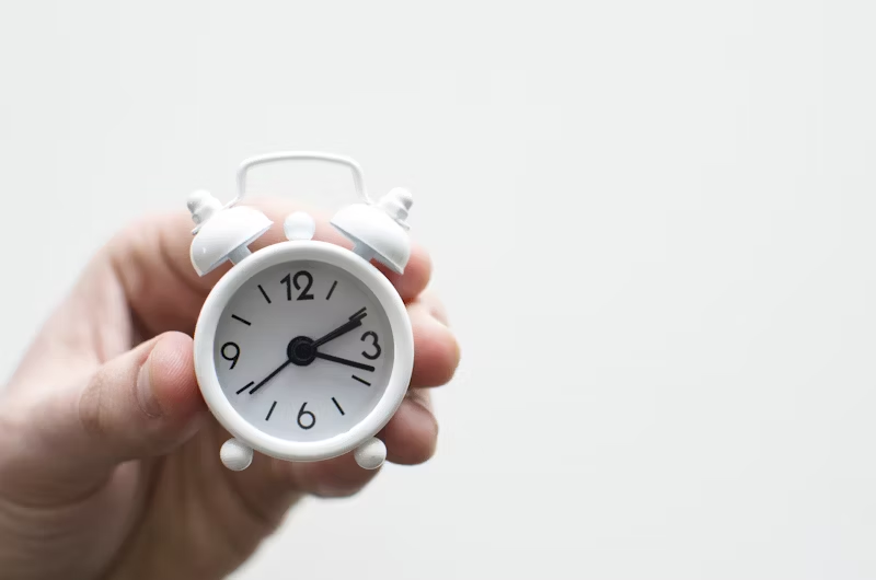 hand holding a small alarm clok
