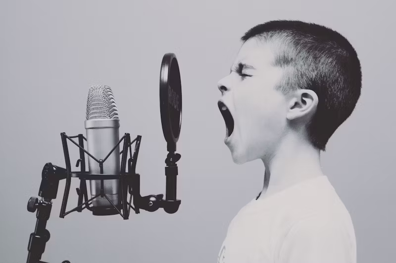 black and white photo of a child in a recording booth yelling