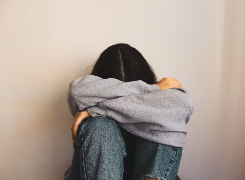 woman curled up hiding her face