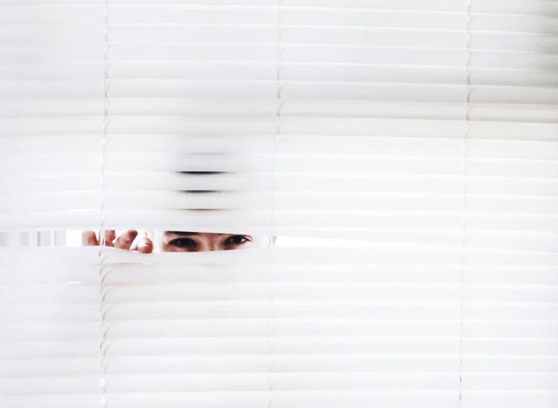 person looking through the blinds