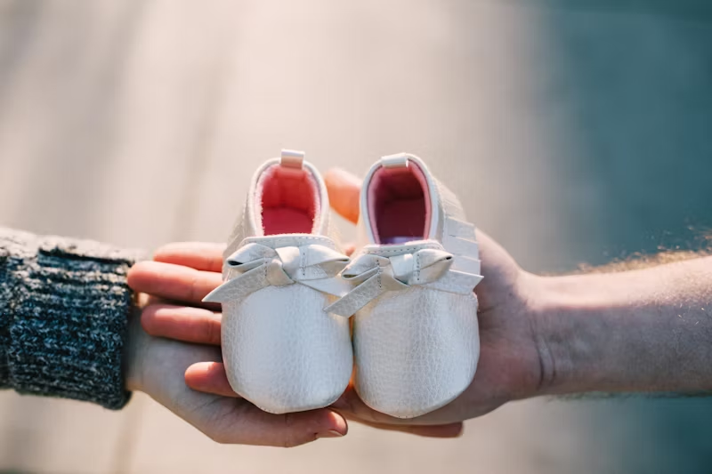 two hands holding baby shoes