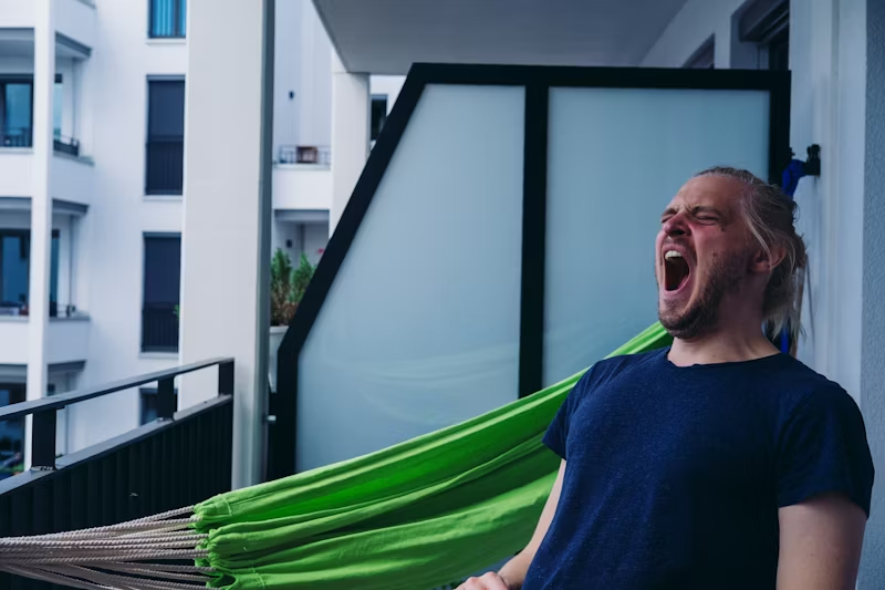 a man on a balcony yawning