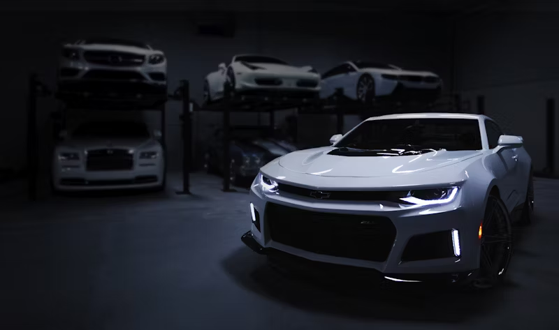 a newer car with their headlights on in a garage