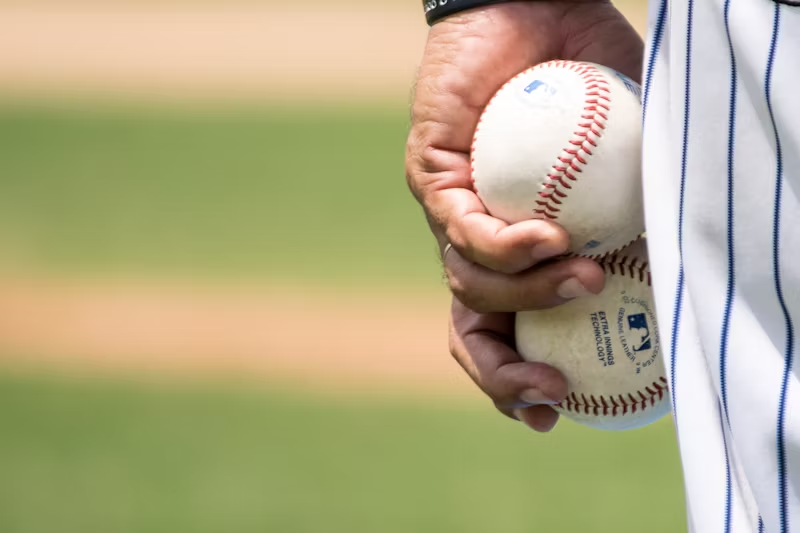 baseball player holding two baseballs 