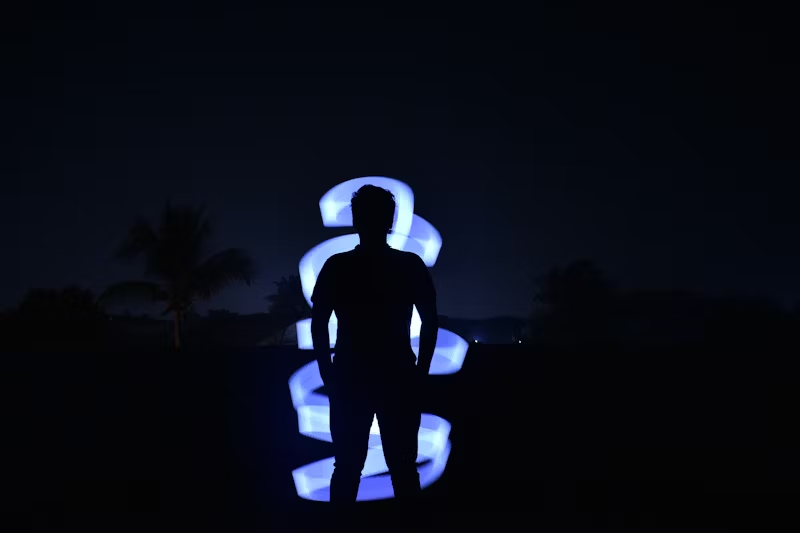 silhouette in front of a lit up art piece
