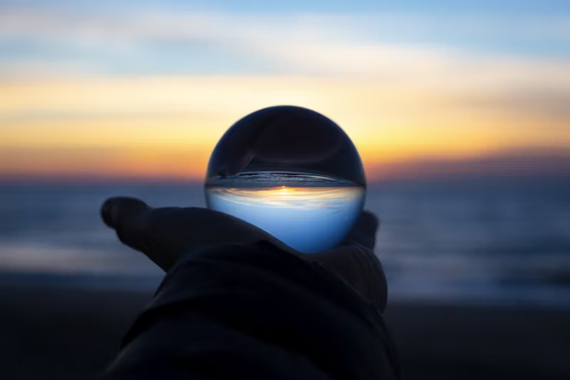 a ball of glass held out in front of the suset