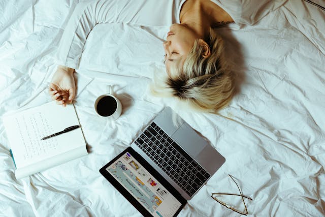 person on bed with laptop sleeping