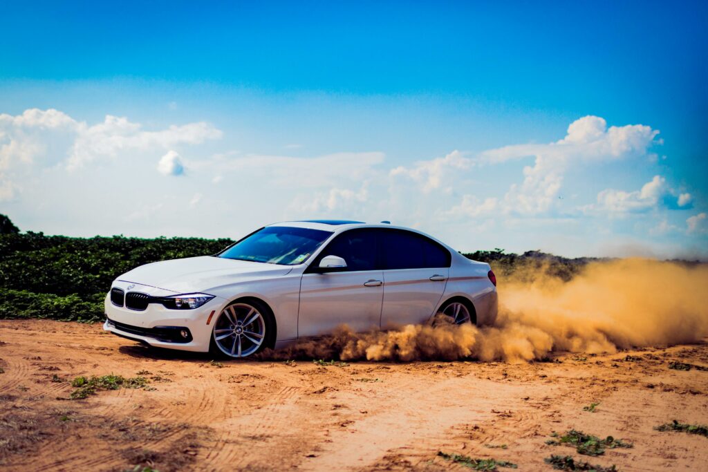 white BMW drifting on sand