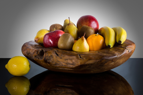 Fresh whole fruits in unique custom wood bowl - High quality healthy concept on black and gray background