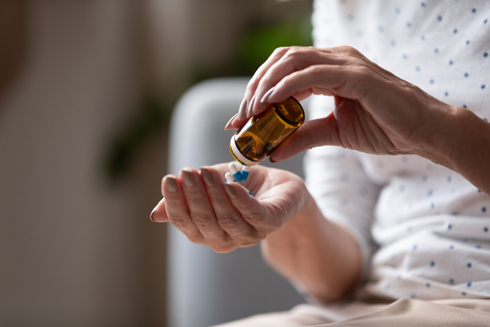 Close up mature woman taking out pills from bottle, supplements or antibiotic, older female preparing to take emergency medicine, chronic disease, healthcare and treatment concept
