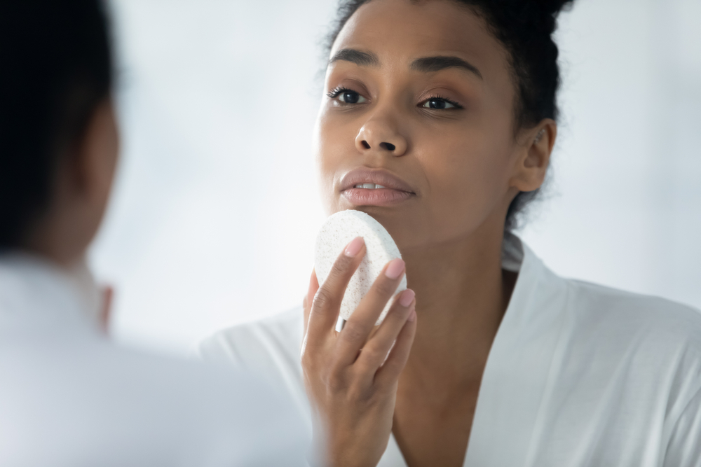 Close up African woman do evening routine cleanses skin using natural facial sponge, gently remove dirt, beauty tool helps renew revitalize skin, keep face perfect, massage procedure, skincare concept
