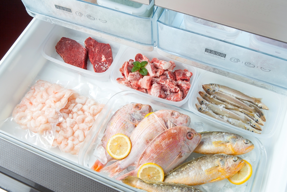 different frozen meat on the opening freezer shelves. food storage.