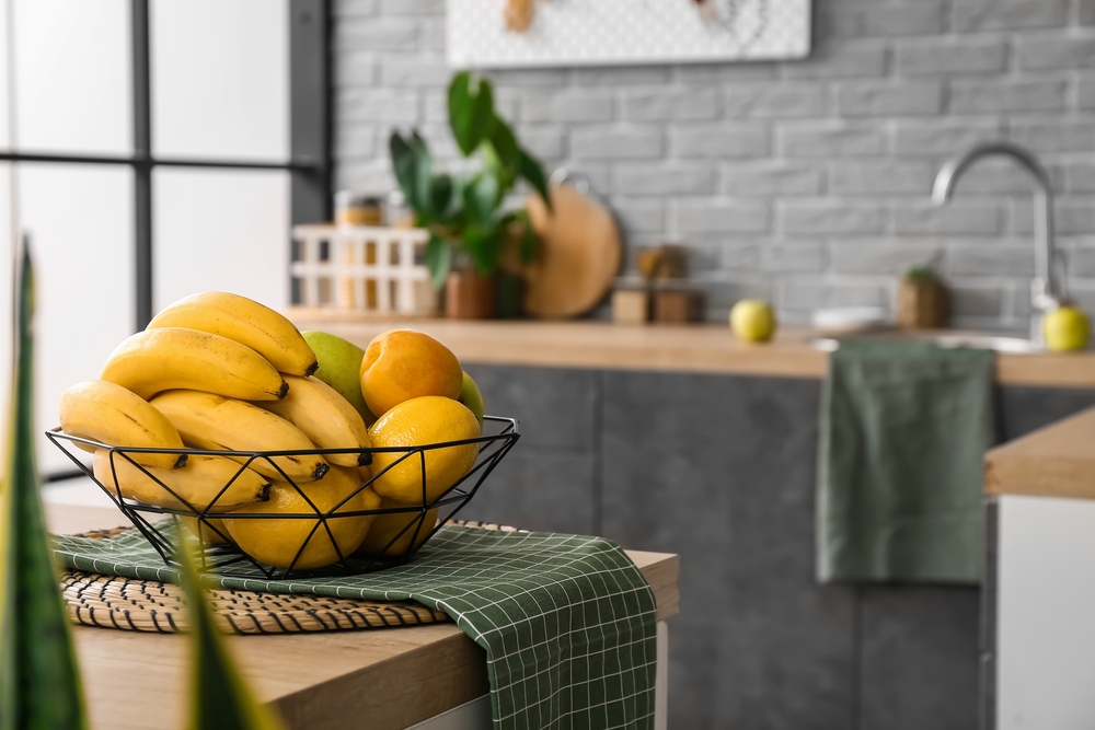 Basket with delicious fruits on table in kitchen
