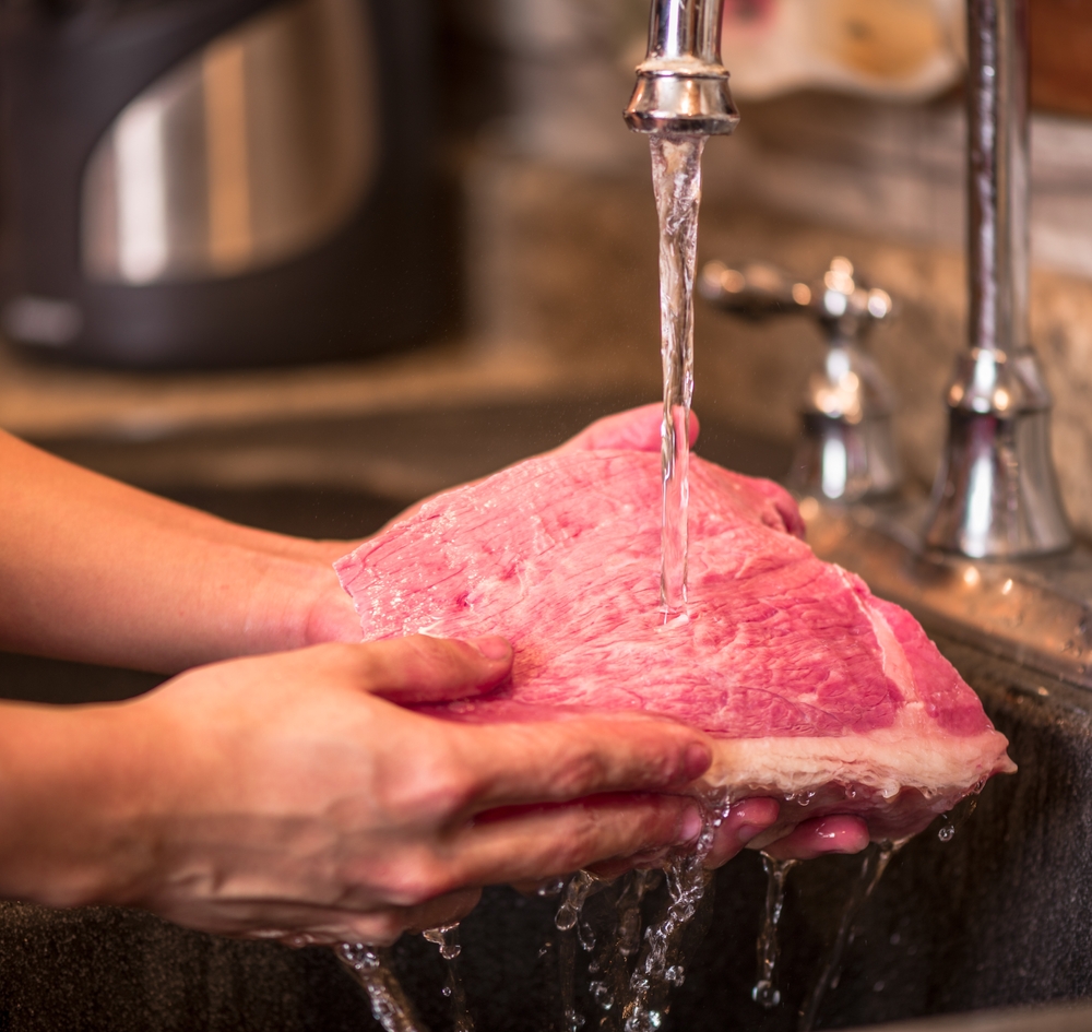 Hand washing meat with water from the sink