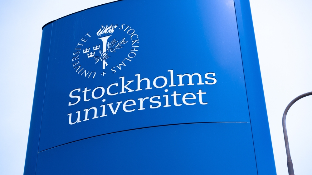 Stockholm, Sweden - 05.22.2022: Stockholm University logotype on a blue metallic board next to a busy highway.