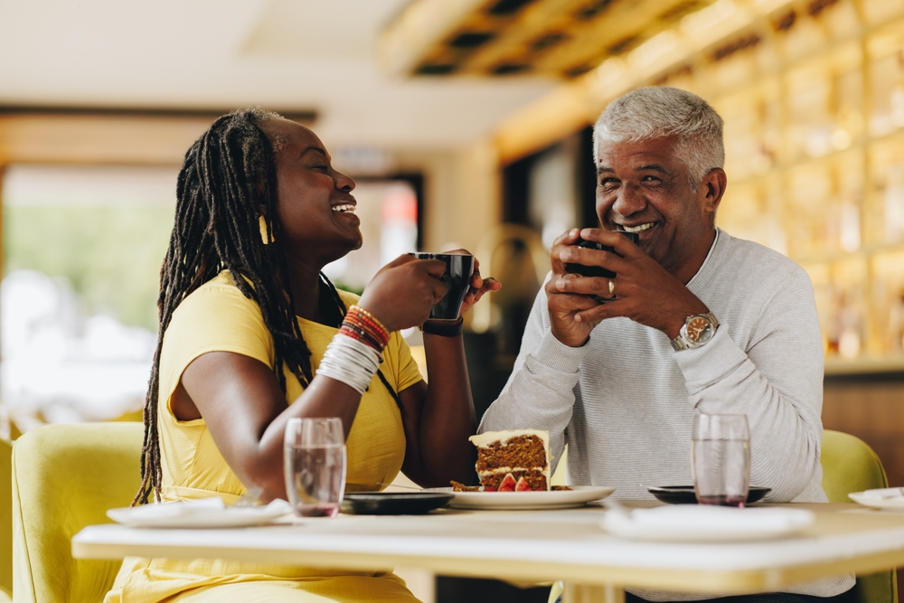 Happy senior couple laughing cheerfully while having coffee together in a cafe. Carefree senior couple having a good time in a restaurant. Mature couple enjoying their retirement together.
