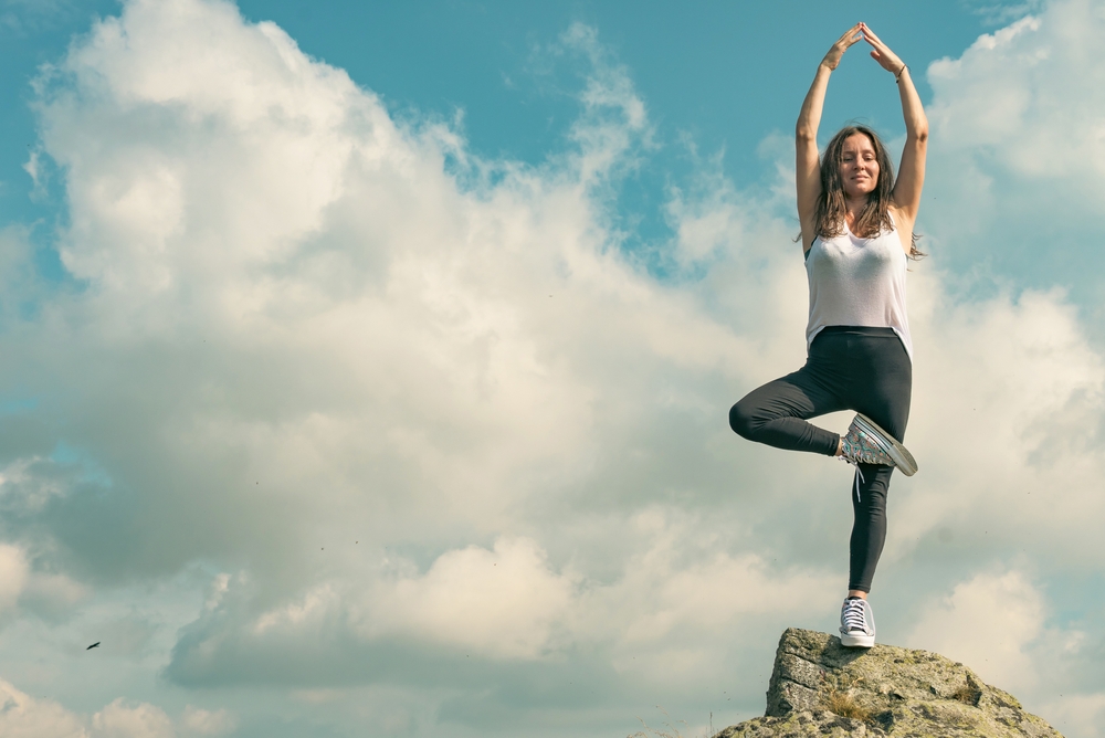 A beautiful woman practices yoga and meditates on a mountain top. Strong and independent women - concept.
