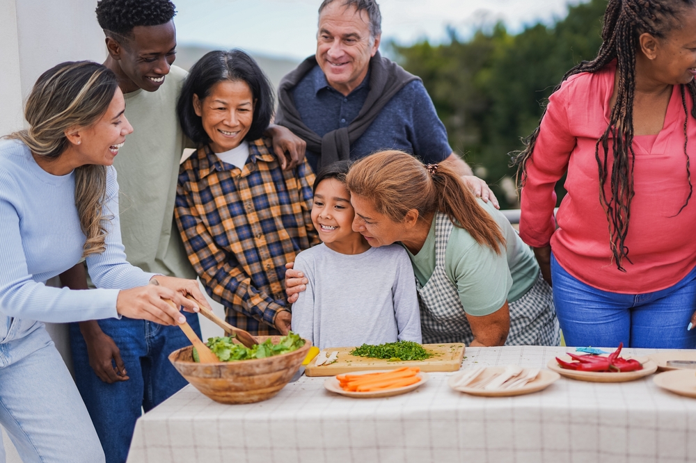 Multiracial people having fun preparing food on rooftop terrace for barbecue - Grandmother having tender moment with grand daughter