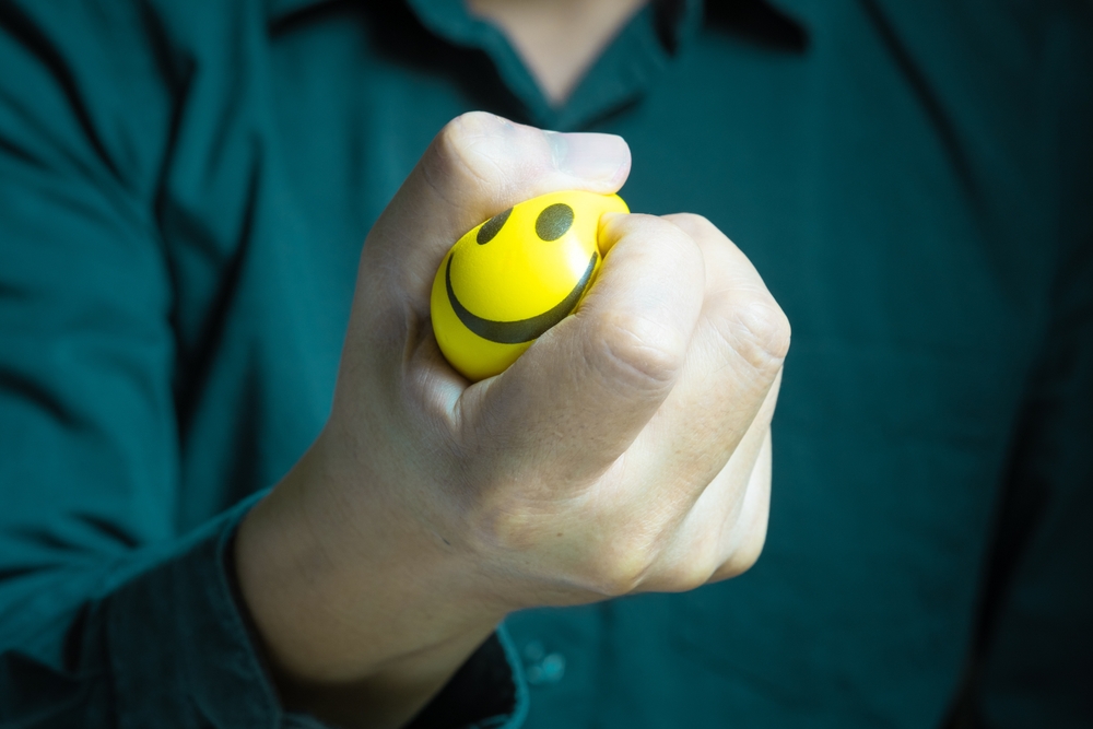 Hands of man with a gentle personality He exhibits stressful behavior from work, and he squeezes the red ball expressing emotion, anger, displeasure. Medical concepts and emotional regulation
