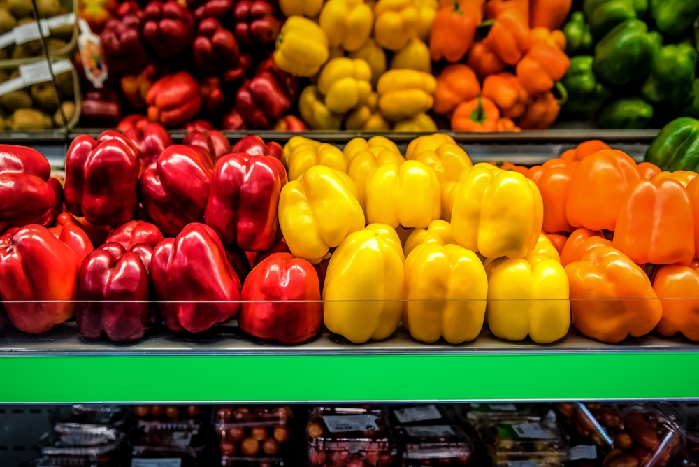 Raw juicy red, yellow and orange bell pepper on the shelf in the supermarket. Sweet pepper on grocery store display. Food and drink theme