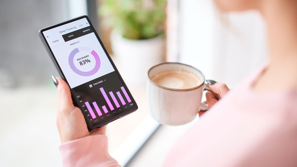 Close Up Of Woman Looking At Sleep Tracking App On Mobile Phone At Home
