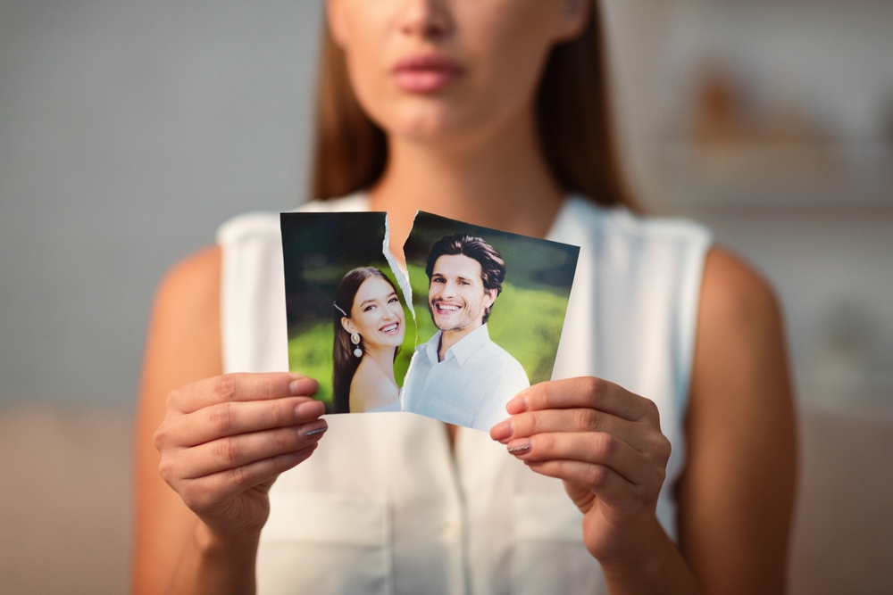 Breakup Concept. Sad Girl Ripping Wedding Photo With Ex-Husband After Divorce Indoor. Selective Focus