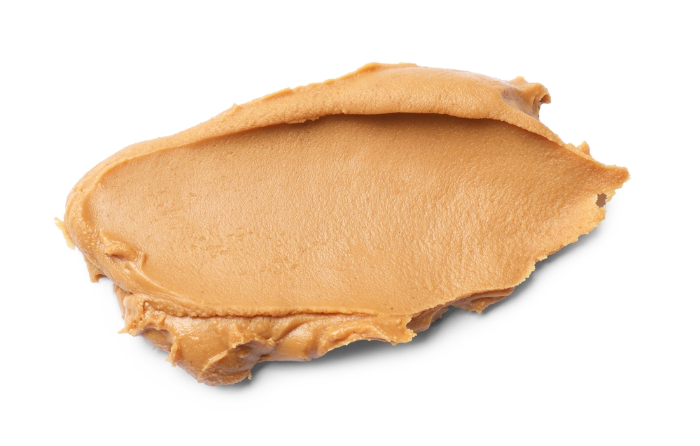 Tasty peanut butter on white background, top view
