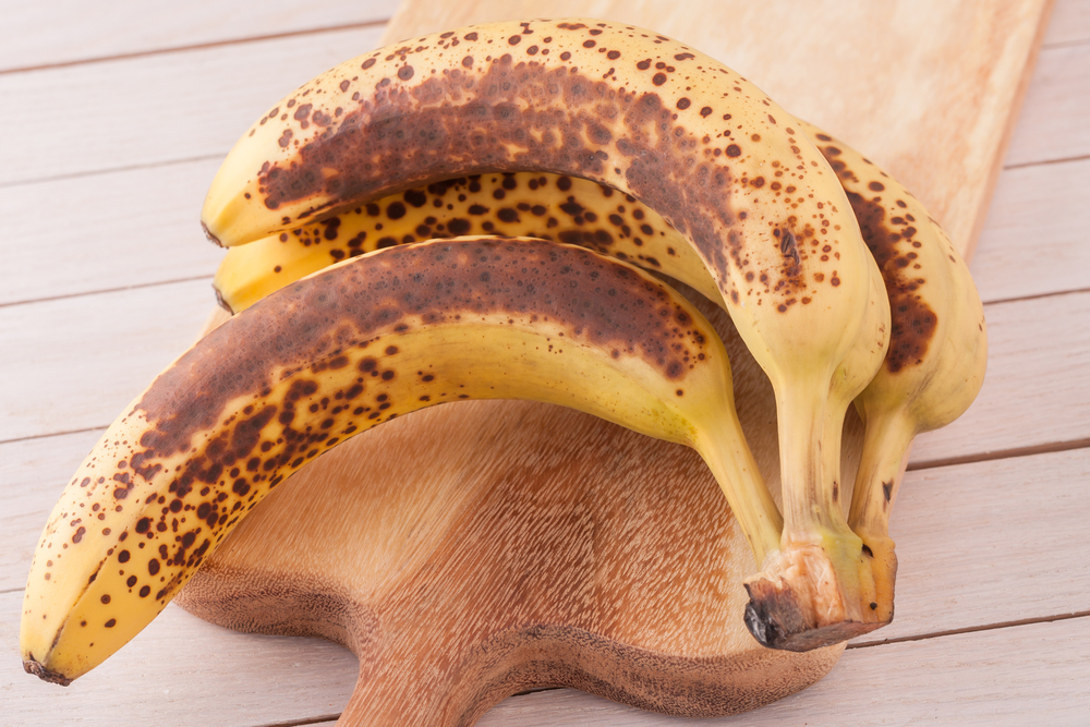 close up a bunch of very bananas on a wooden chopping board
