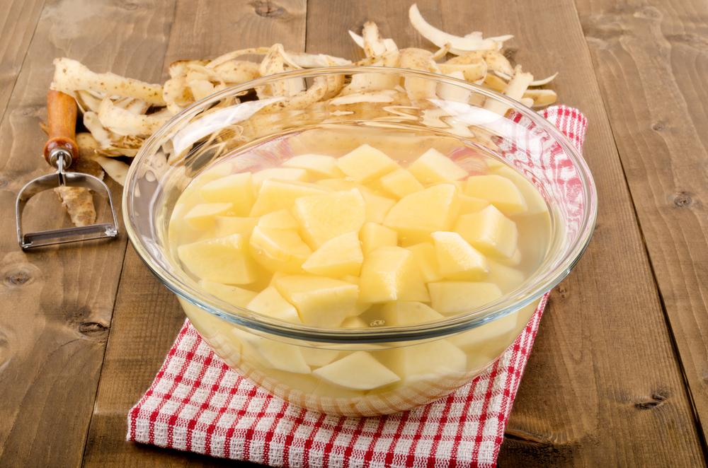 diced potatoes in a glass bowl with water to remove the potato starch
