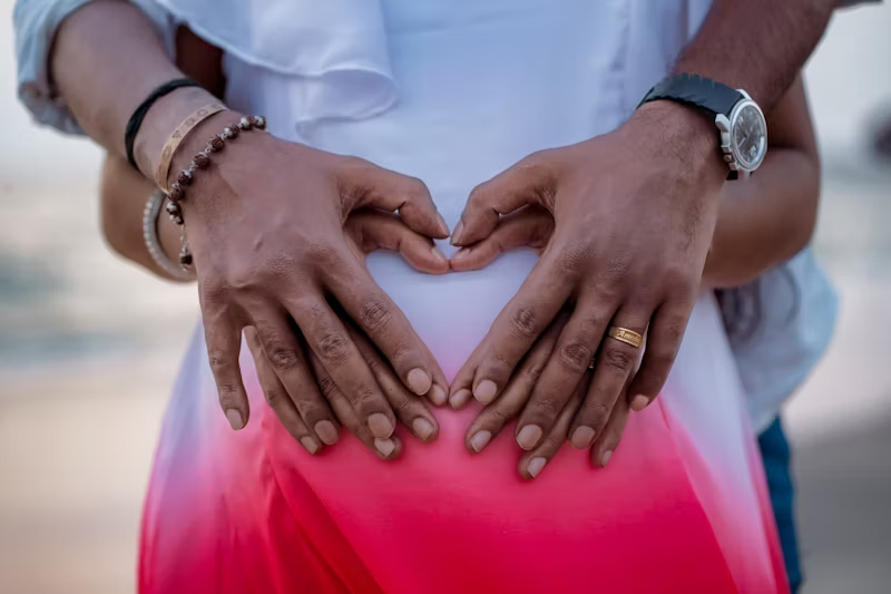 two sets of hands making hearts over someones stomach